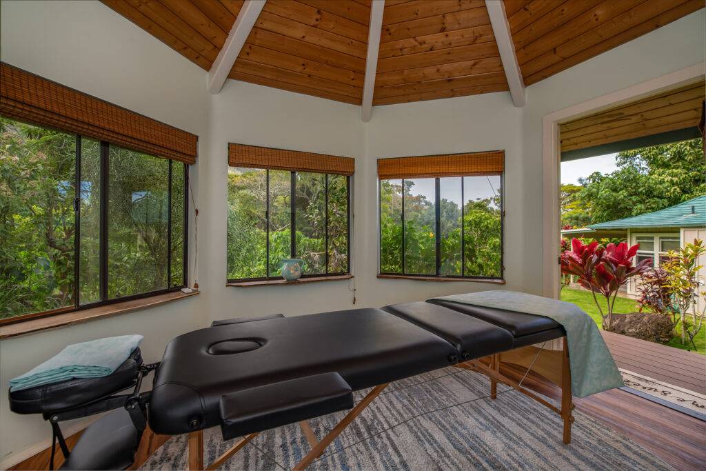 Cottage gazebo interior with massage table facing windows and open door