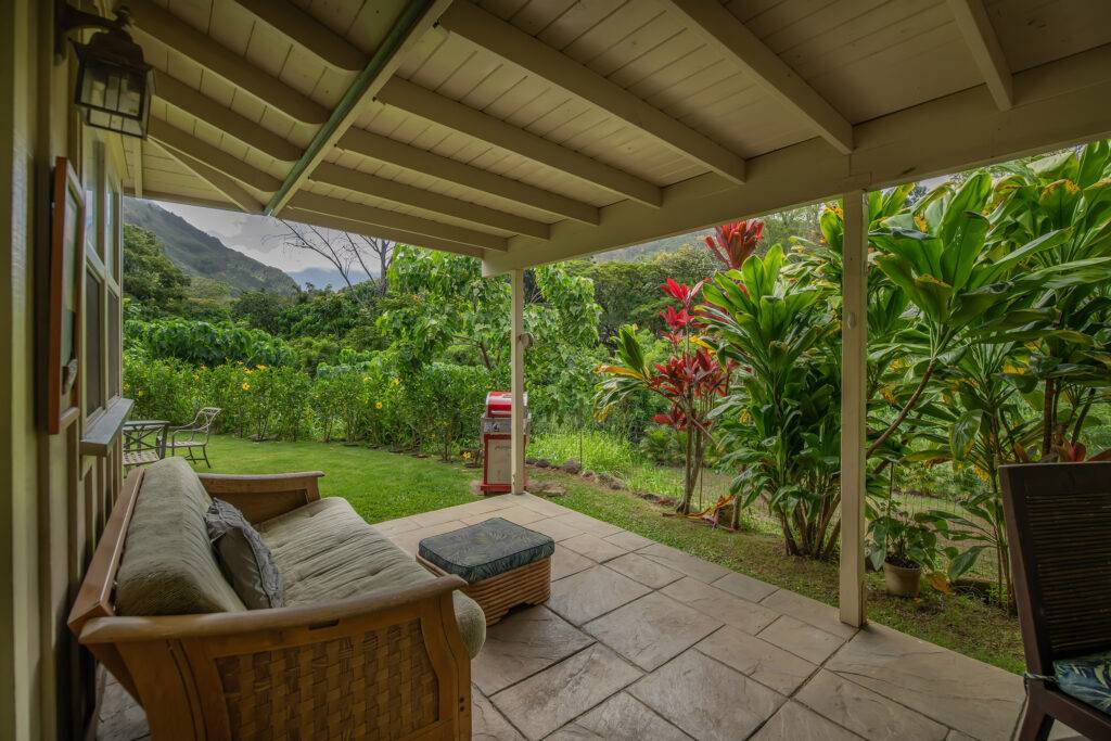 Couch on Lanai with view of outdoor dining, barbecue , tropical plants and the inviting recesses of Iao Valley