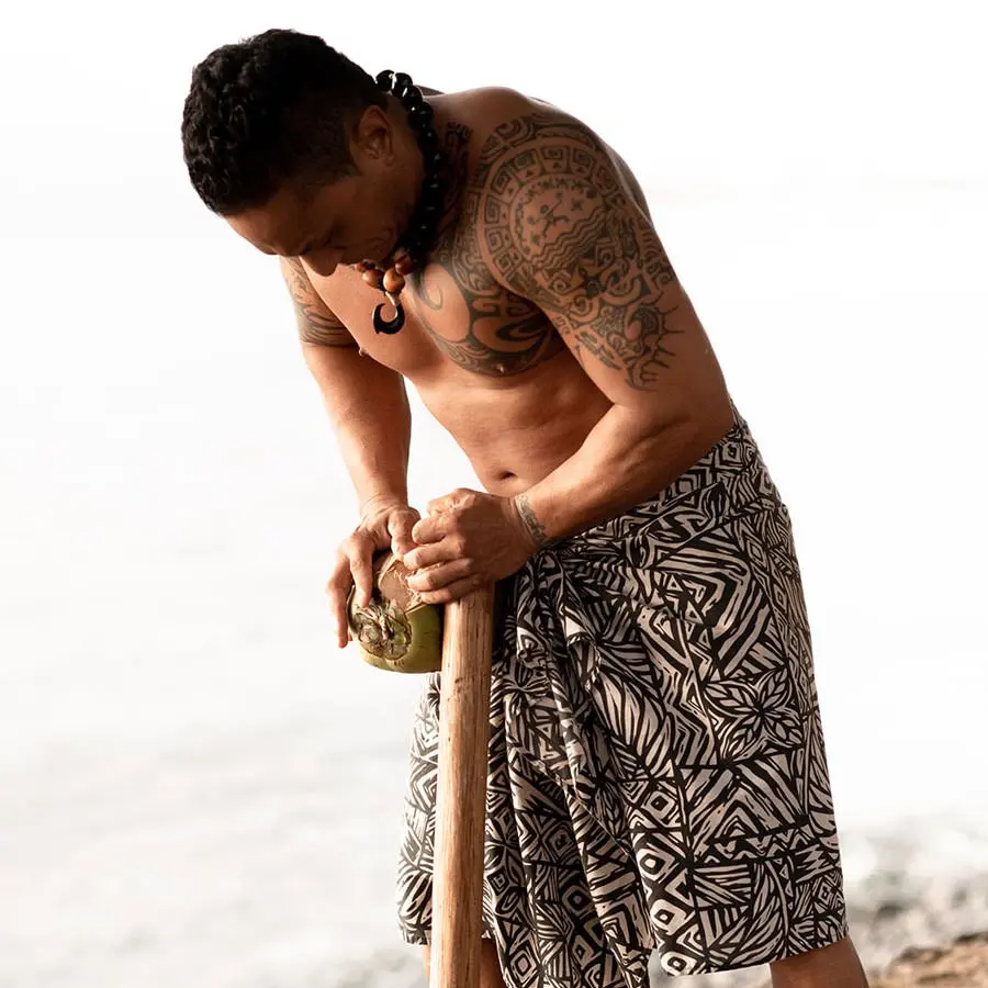 A man husks a coconut at the Old Lahaina Luau